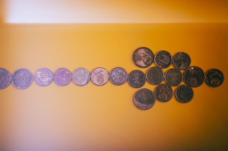 coins euro cents in the form of arrows lie on a yellow background. Conceptual. Closeup.の写真素材