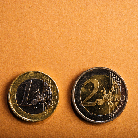 coins one and two euros on a background of cardboard. Closeup. Currency of the Euro Union.の写真素材
