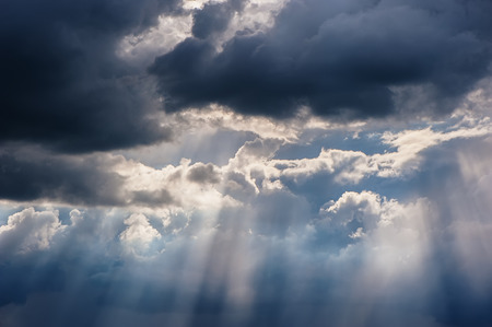 rain and sunrays on a blue sky. Stormy dark clouds. Spring weather.の写真素材