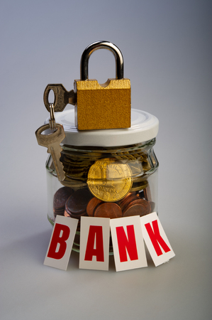 glass jar with coins and an inscription bank with a padlock with keys on a light backgroundの写真素材