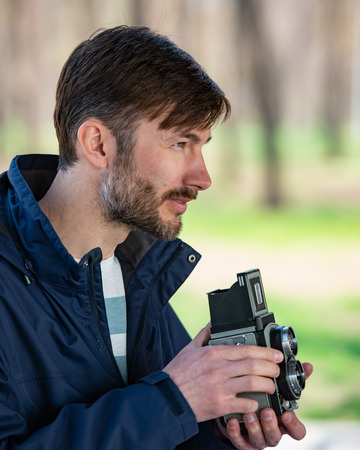bearded photographer photographs with enthusiasm the film camera.  Photographing a two-objective old...