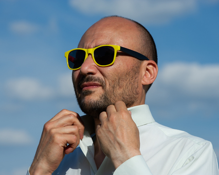 portrait of a businessman in modern sunglasses against a blue sky background. Creative portrait of a man.の写真素材