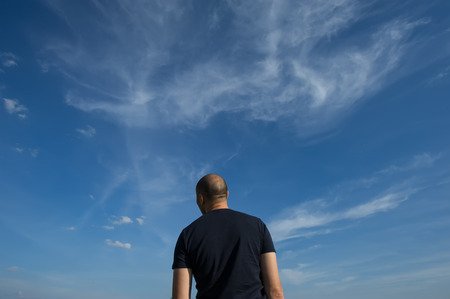 man is standing with his back in the field and staring into the distance at sunset. The traveler is looking into the distance.の写真素材