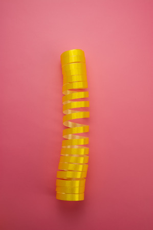 yellow twisted ribbon lies on a pink backgroun. Web banner. New year concept.の写真素材