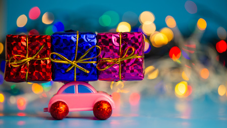Pink toy car delivers Christmas presents on the background of the night city. Web banner. For the blog.の写真素材