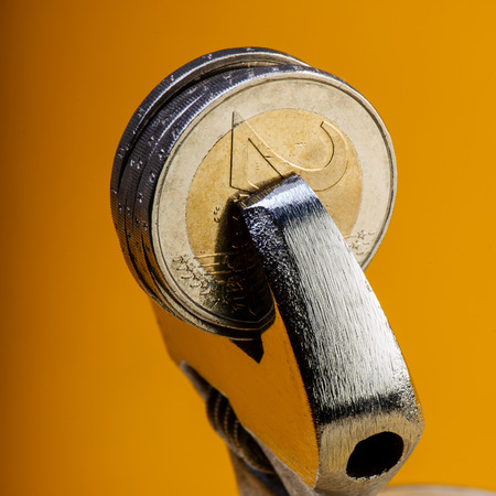 coins of two euros are clamped in a wrench. Business concept.の写真素材