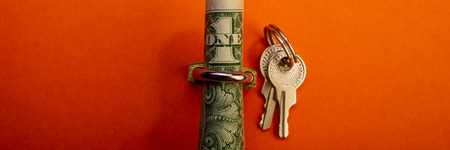 rolled up one dollar in the padlock and keys on an orange background. Business concept. Web banner.の写真素材