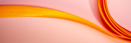 Yellow ribbon lies on a pink background. Web banner.の写真素材