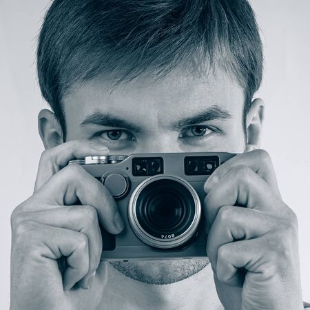 Portrait of a young photographer taking pictures with a film camera, close-up. The process of taking...