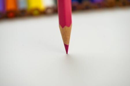 Pink pencil on a blurry background of colored pencils aimed at white paper vertically. For your design.の写真素材