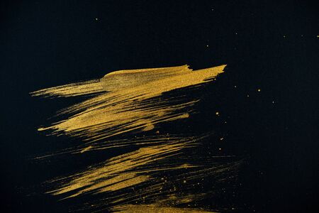 strokes with golden paint brush on black paper. Abstract background.の写真素材