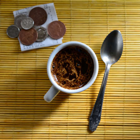 check and coins with a cup of coffee and a spoon lie on a table in a cafe. Web banner. Business concept.の写真素材