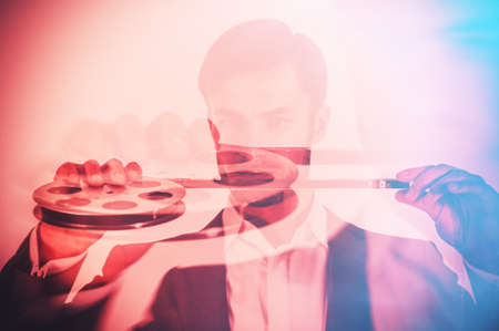 cameraman is viewing the captured film with an analog film camera, close-up. Business concept.の写真素材