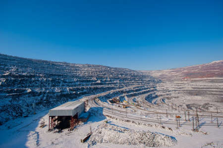 Opencast iron ore mining in winter. Loading and delivery of mined ore by railroad and conveyor...