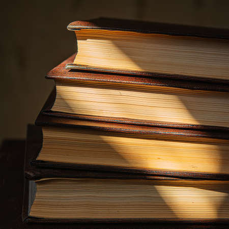 stack of old books for reading lies on the table in the room. Vintage books lying on the table in a...