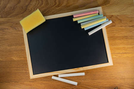 Crayons lie on a black chalkboard on the surface of an oak table. Creative concept.の写真素材