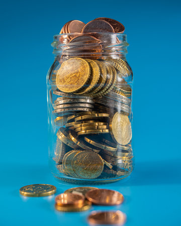 glass jar with coins and coins lying around. Business concept.