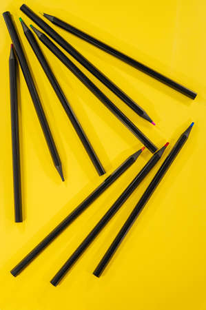 black wooden pencils lie on a yellow background. Cover. For design.