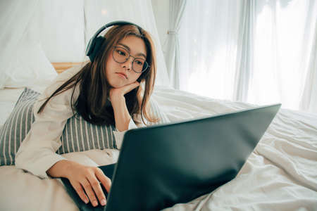 Beautiful asian young woman wearing glasses and headphones listening music or watching movie with...