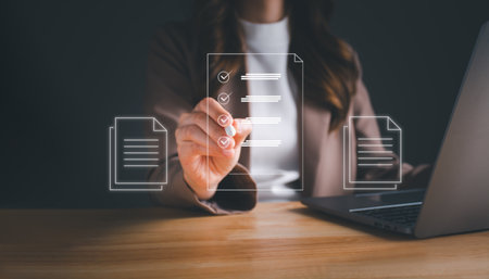 Businesswoman working on laptop with electronics document icons by virtual notebook screen using a stylus pen checking list on a digital tablet. E-document management Paperless workplace concept.の写真素材