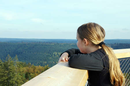 A blonde girl drops the views over the wooded hills of the Black Forest roam. The teenager stands on the 40 meter high viewing tower of Baumwipfelfada in Bad Wildbad. A veritable sea of forest extends from this viewing platform. No Pylon, no bridge or chiのeditorial素材