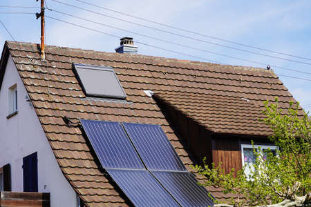 Old farmhouse with solar panels on the tiled roofの写真素材