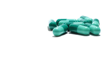 Medicine pills spilling out of a bottle on a colored bottle background.