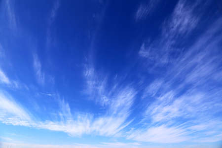A blue sky with sun, sunbeams and clouds.
