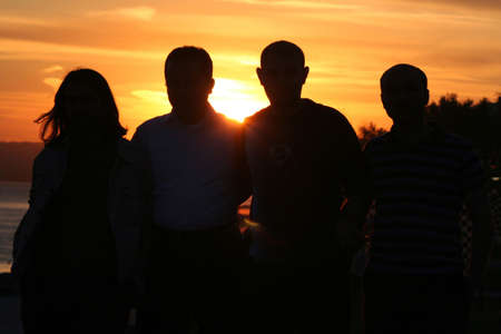 Friends are near a sea with sunset time(cool background)の写真素材