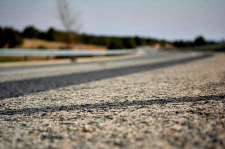 defocused asphalt detail on a curve of a road with guardrailsの写真素材