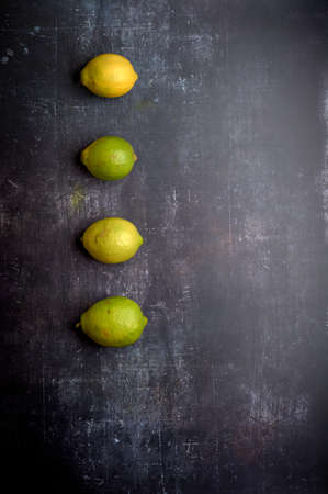 set of yellow and green lemons on a dark, black, cement, metallic, marble and stone backgroundの写真素材