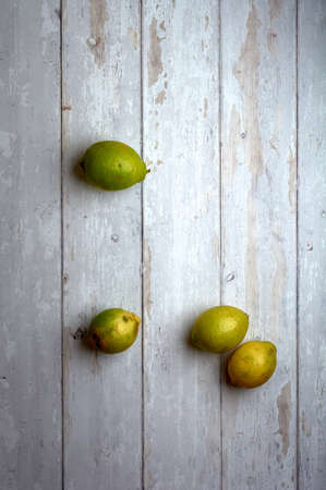 yellow and green lemons on a white and cream wooden backgroundの写真素材