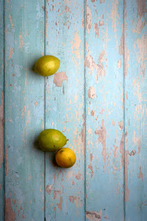 yellow and green lemons on a blue wooden backgroundの写真素材