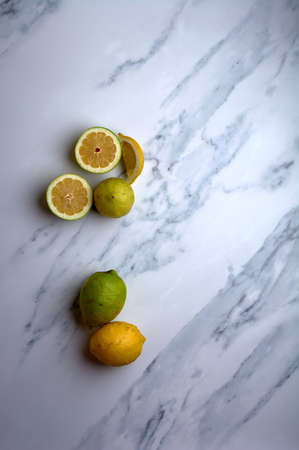 set of cut and uncut lemons on a white marble backgroundの写真素材