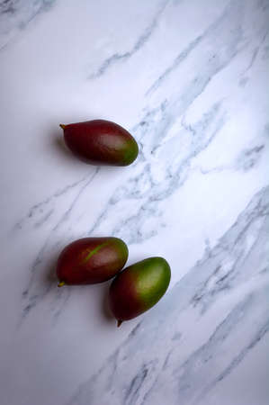 set of cut or uncut mangoes on a white marble background