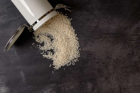 detail of a white ceramic jar with a lid with rice inside on a dark backgroundの写真素材