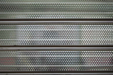 detail of a gray metal shutter of a store or establishment with many holes