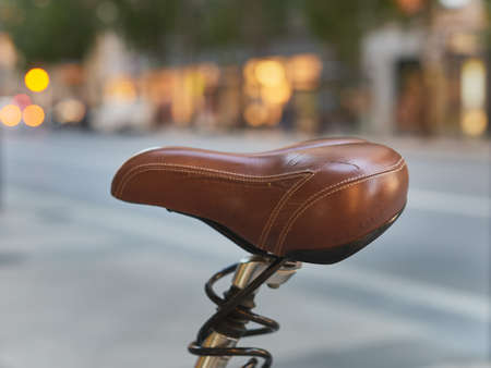 detail of a worn brown leather seat of a bicycle on a public streetの写真素材