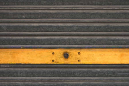 detail of a metal shutter of a garage with yellow stripeの写真素材