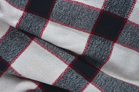detail of a black, white and blue plaid blanket with red stripesの写真素材