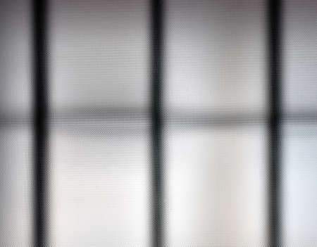 detail of a translucent textured glass in a window and a grille behind itの写真素材