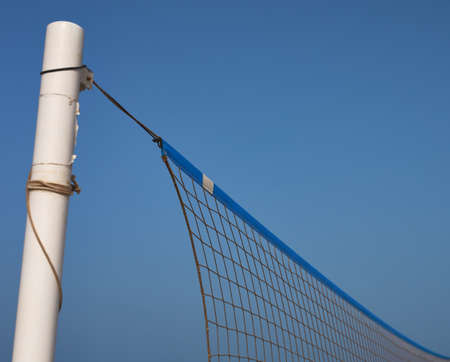detail of a beach volleyball pole and net on a blue backgroundの写真素材