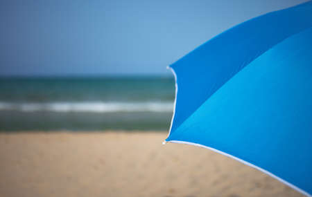 detail of a blue umbrella on a beach with the sea and sky in the backgroundの写真素材