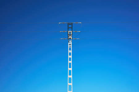 detail of a power cable conduction pole against a blue sky backgroundの写真素材