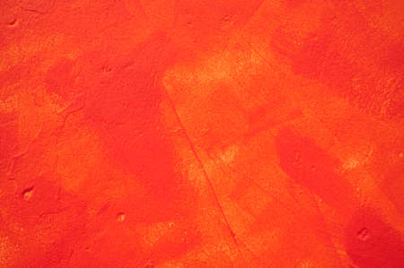 detail of an irregular stucco wall painted red or orange