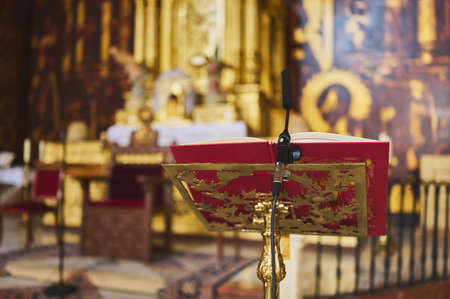 detail of a gilded lectern with book and microphone on the altar of a church