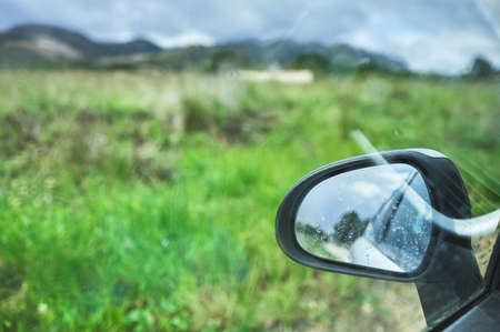 detail of a view of a rearview mirror of a car in a green grass field