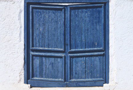 detail of an old blue wooden door on a white wallの写真素材