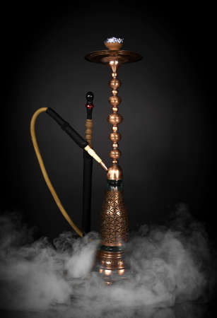 East smoking hookah. Arabian shisha. dark background with smokeの写真素材