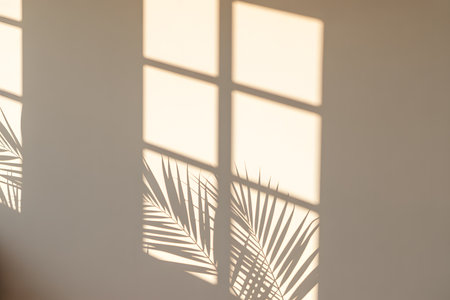 Minimalist interior with soft natural lighting, featuring a ribbed white vase with pampas grass and a ceramic bowl, accented by dramatic diagonal shadows on a beige wall.の素材